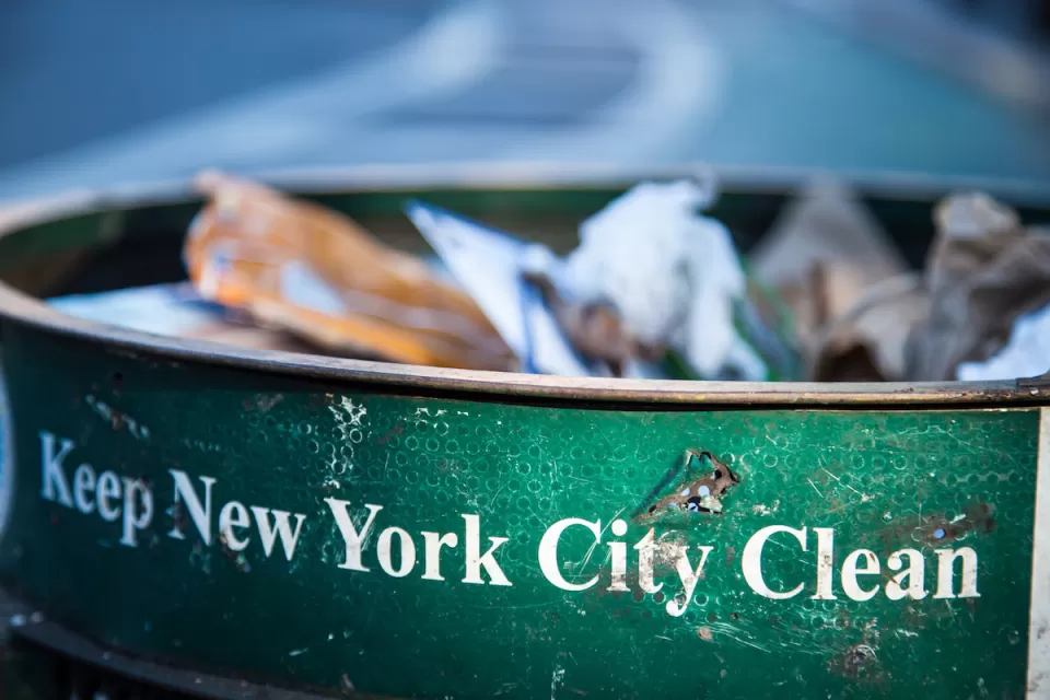 Close-up of green New York City public trash can with white text "Keep New York City Clean."